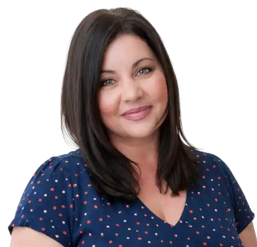 Professional woman smiling in navy polka dot blouse, supporting education behavior consultants.