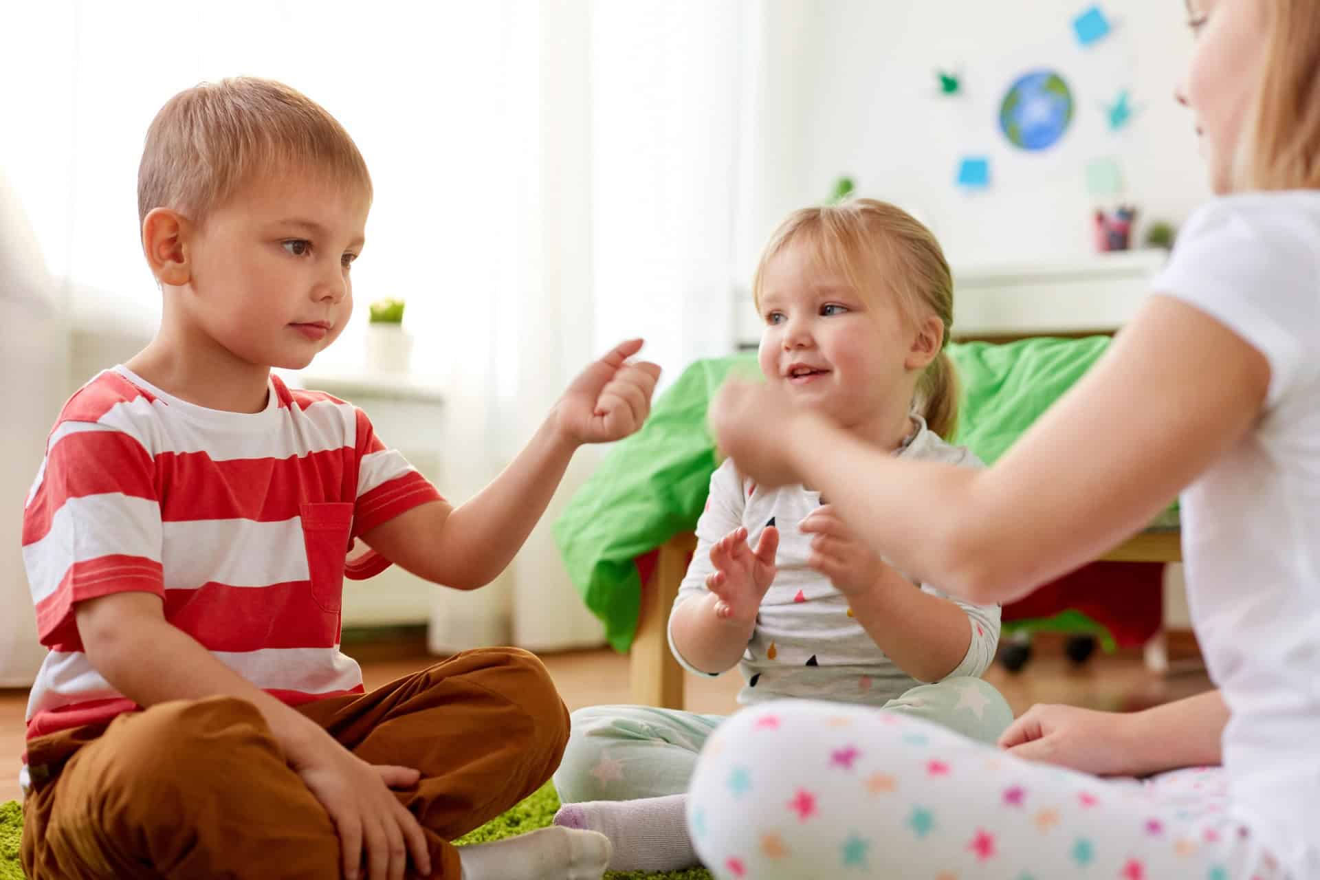 Friendly children engaging during expressive behavior therapy session with a counselor.
