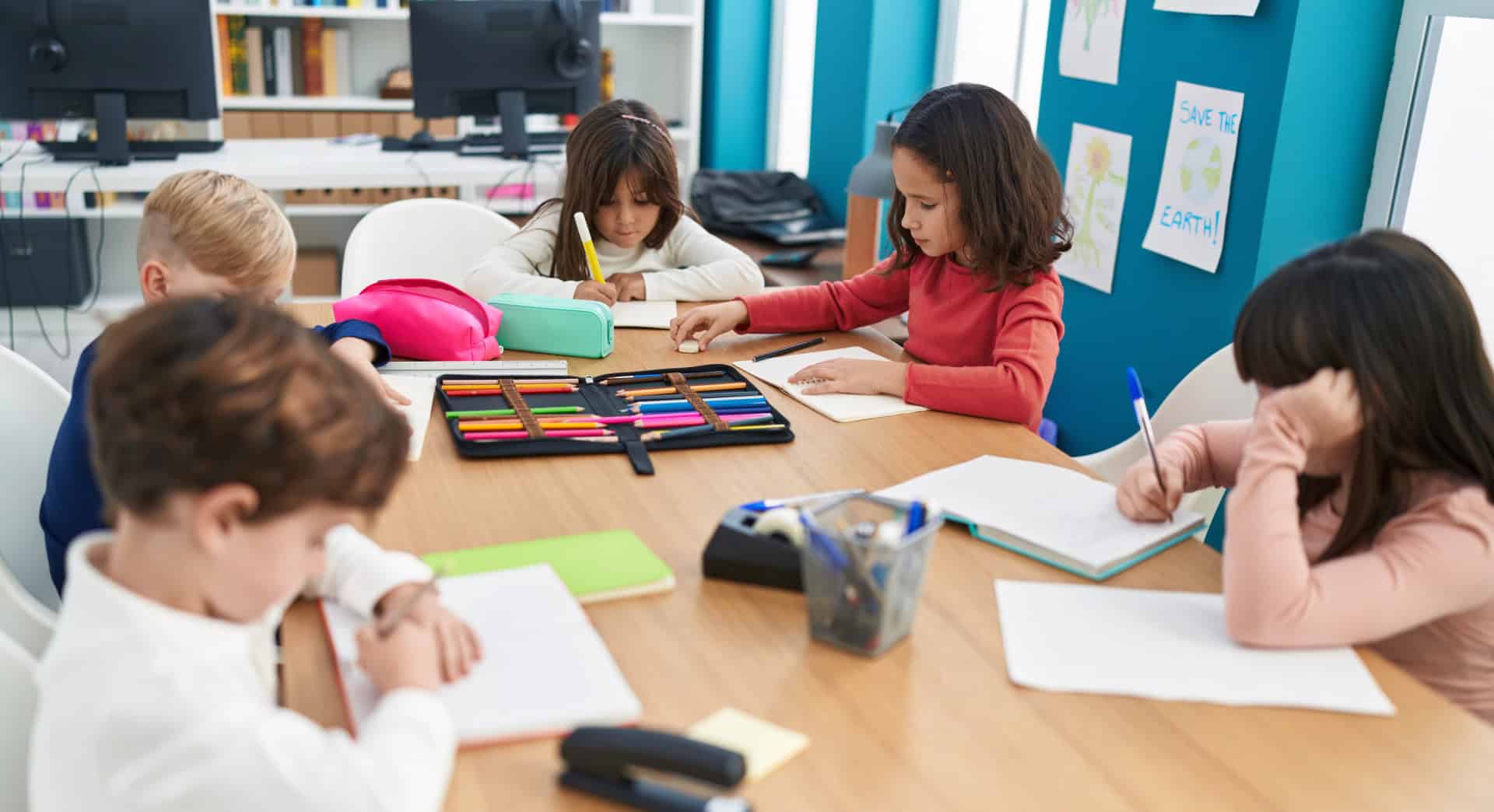 Children working together on educational activities at a classroom table, supported by Education Behavior Consultants.