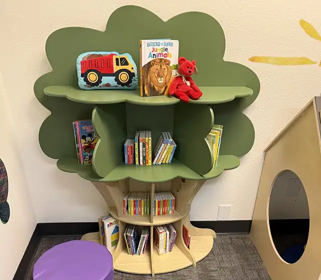 Colorful children's bookshelf designed like a tree with books and toys for engaging educational play.