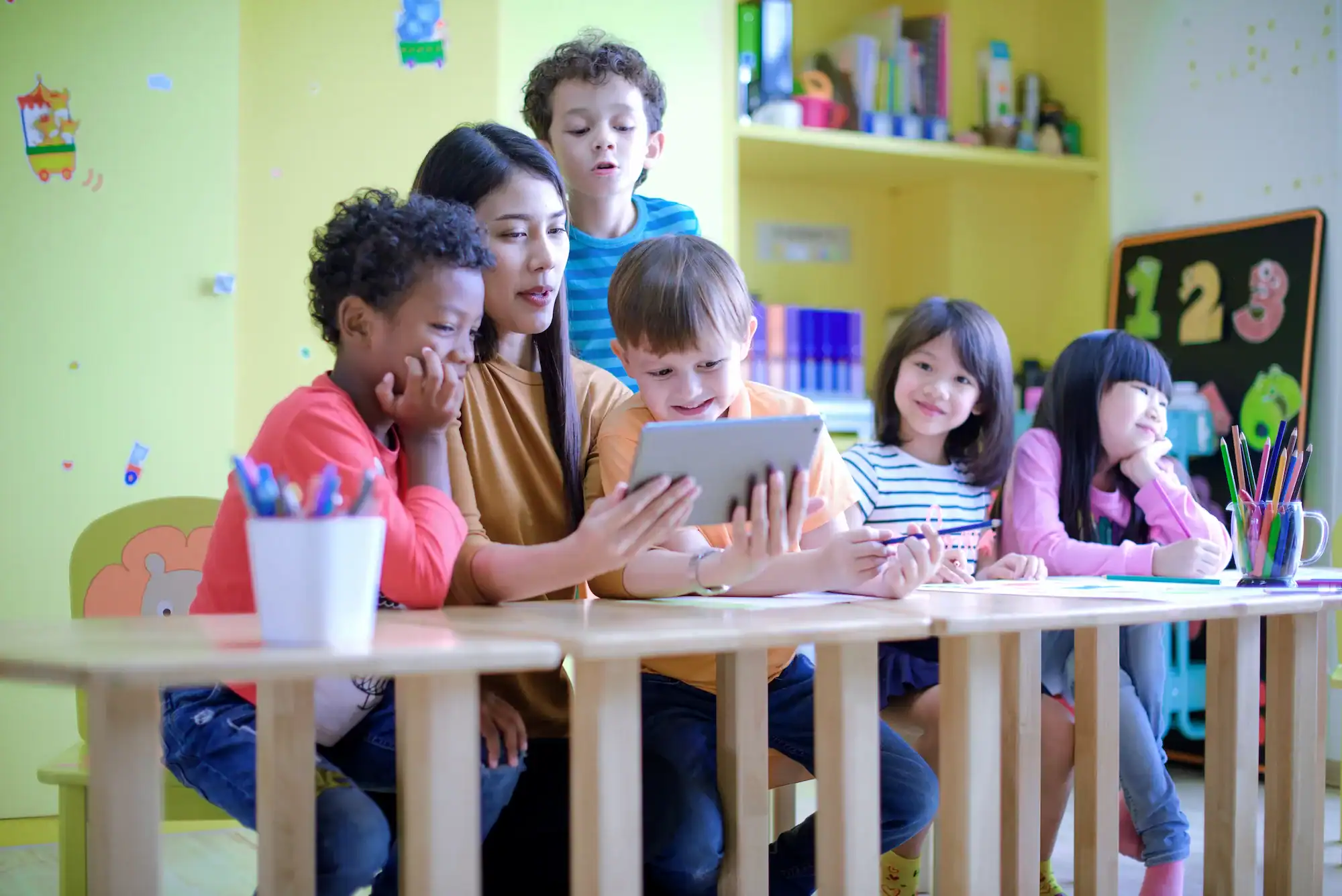 Teacher and children using tablet in classroom for education behavior management.