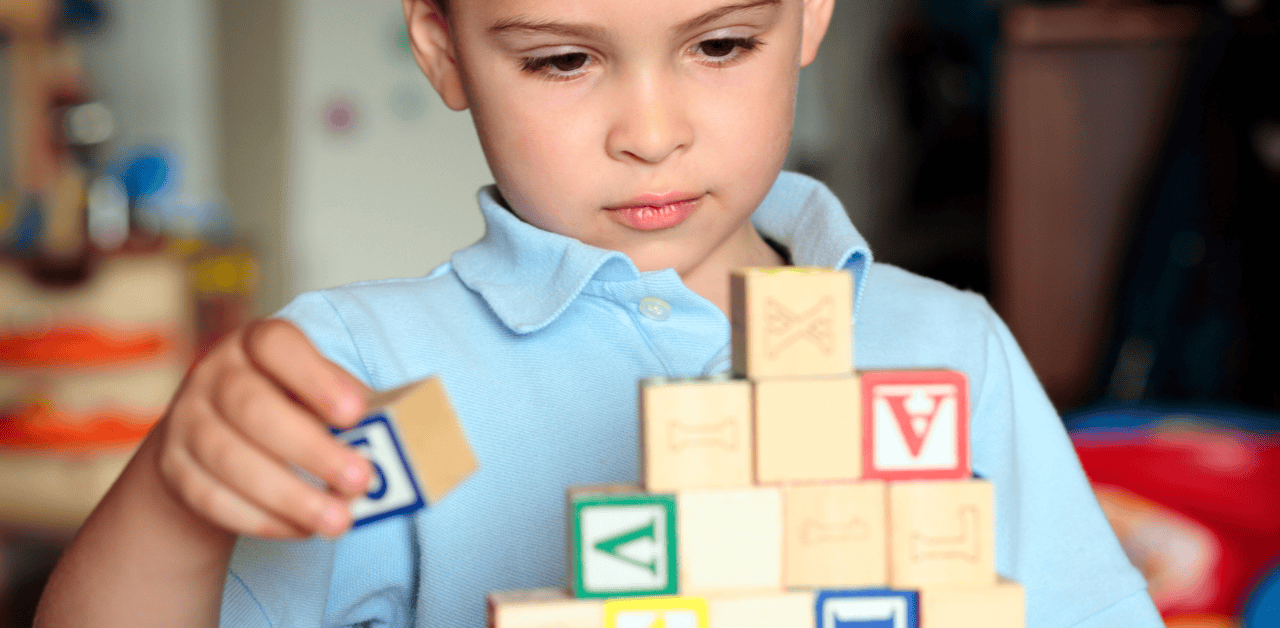 Child stacking educational blocks to support autism behavior therapy.