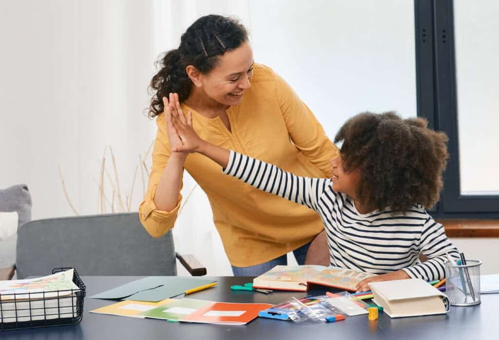 Teacher and child giving a high five in classroom setting.