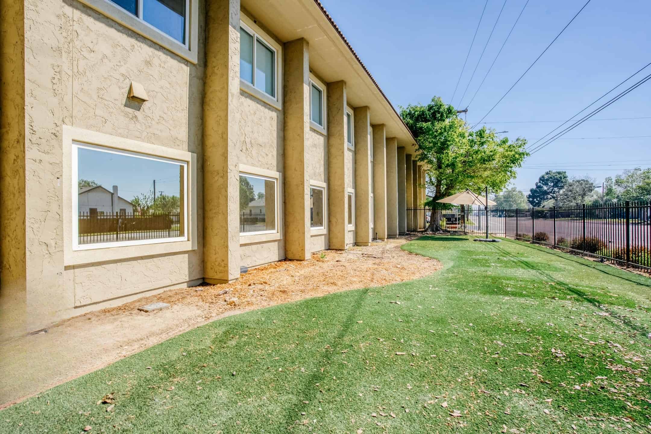 School building exterior with large windows and a grassy yard.